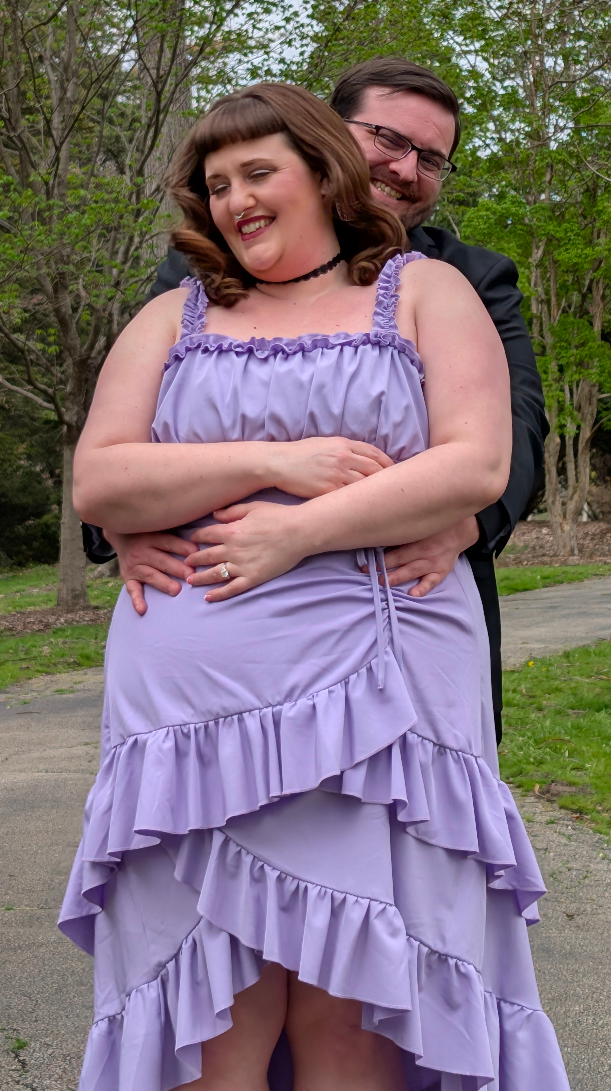 Randall hugging Marina from behind while both smile.