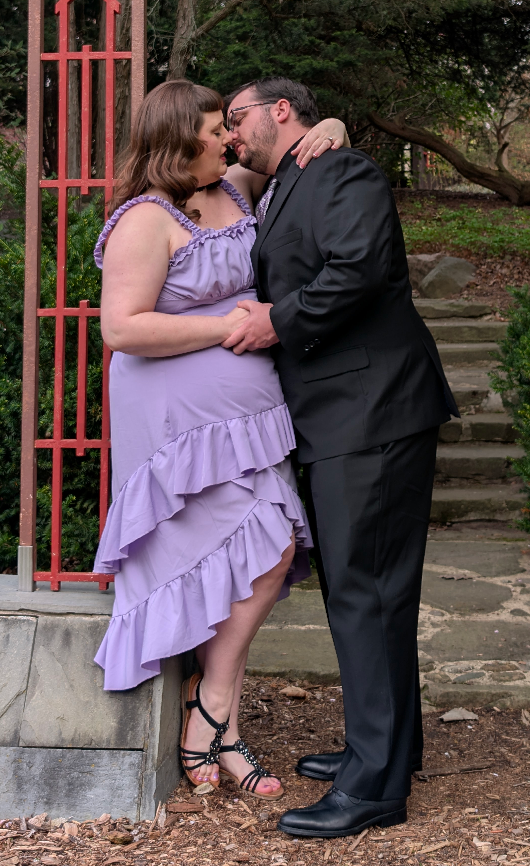 Marina and Randall sharing a kiss by a garden arch.